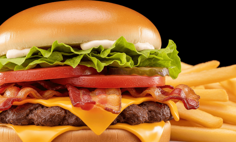 Close-up of Wendy’s Jr. Bacon Cheeseburger with crispy bacon, melted cheese, lettuce, tomato, and a toasted bun, served with fries