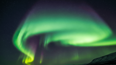 Vibrant green and purple northern lights dancing across the night sky during a strong geomagnetic storm