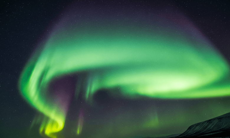 Vibrant green and purple northern lights dancing across the night sky during a strong geomagnetic storm