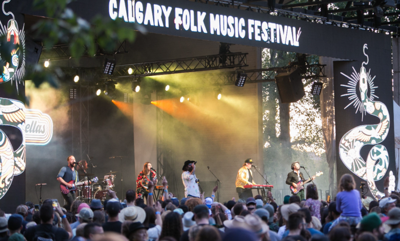 Live band performing on stage at the Calgary Folk Music Festival 2025 with a large audience enjoying the show under festival lights.