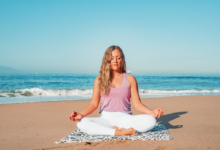 Woman practicing meditation on the beach to reduce stress and improve mental well-being.