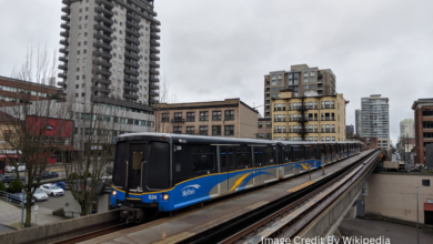 SkyTrain arriving at a station with BC Transit bus nearby in British Columbia