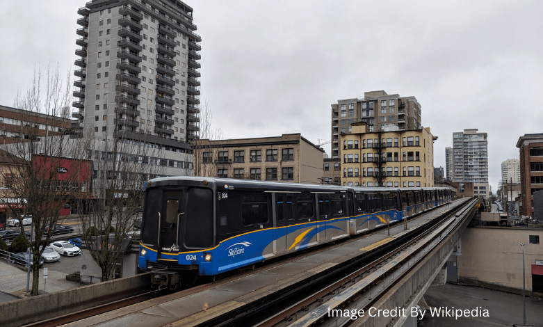 SkyTrain arriving at a station with BC Transit bus nearby in British Columbia