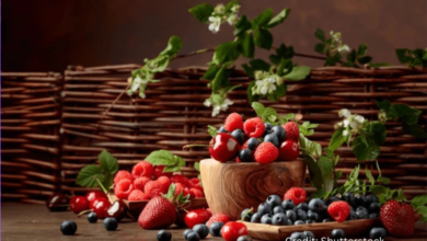 A vibrant flat-lay of mood-boosting foods including salmon, blueberries, leafy greens, yogurt, and dark chocolate arranged on a wooden table.