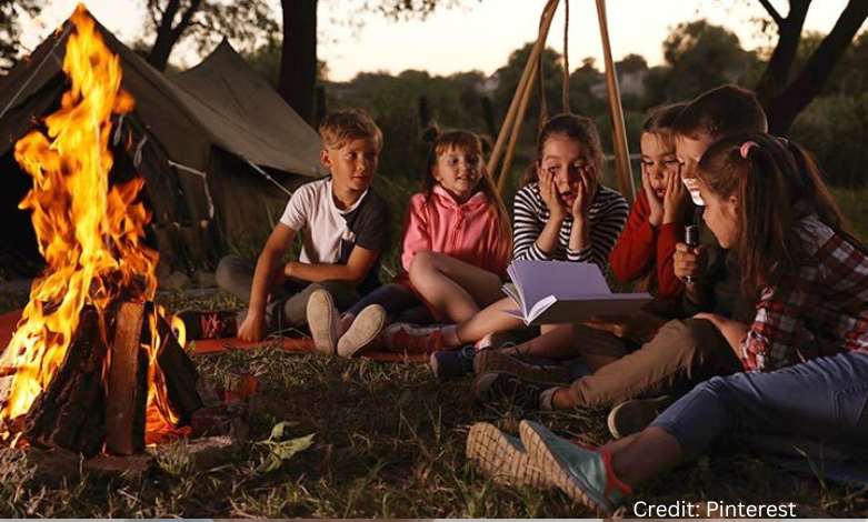 Children at a summer camp in Saskatchewan sitting around a campfire without phones, laughing and bonding in a natural setting