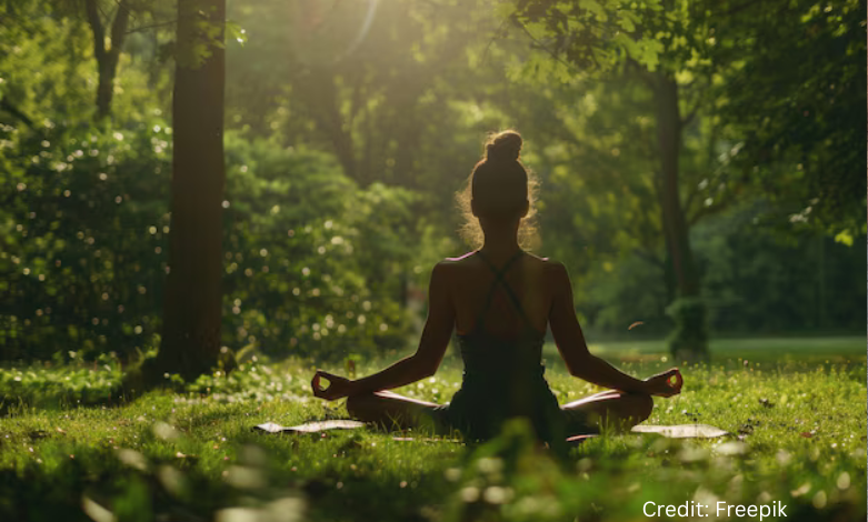 Young woman meditating in a green London park as part of budget wellness routine in the UK