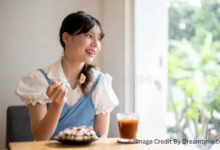 Woman smiling while saving money and enjoying iced coffee at a desk