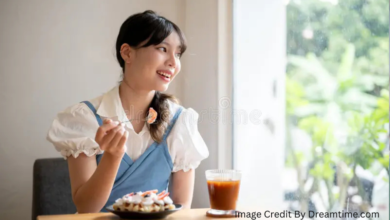 Woman smiling while saving money and enjoying iced coffee at a desk