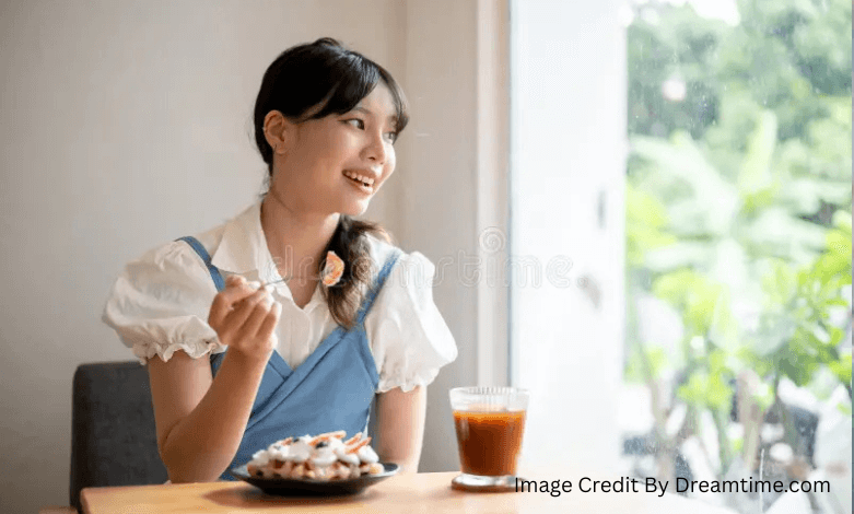 Woman smiling while saving money and enjoying iced coffee at a desk