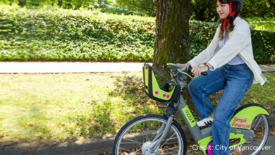 Mobi by Rogers neon green and pink e-bike parked at a Vancouver charging station, highlighting safety and visibility