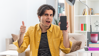 flagship phones worth it for a simple life young man giving a thumbs up while showing a basic smartphone, demonstrating satisfaction with a simple device.