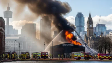 Firefighters battling the Hotspur Press fire with smoke rising over Manchester city centre