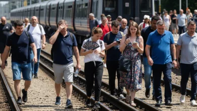 Passengers walking along railway tracks after Thameslink train evacuation during London heatwave