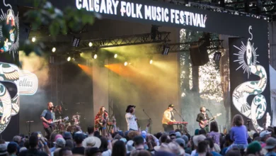 Live band performing on stage at the Calgary Folk Music Festival 2025 with a large audience enjoying the show under festival lights.