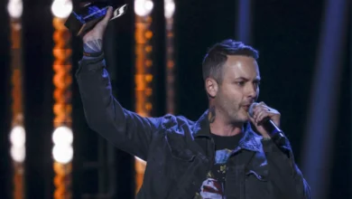 Dallas Smith performing on stage during his 51-date Canadian tour, holding an award and microphone.