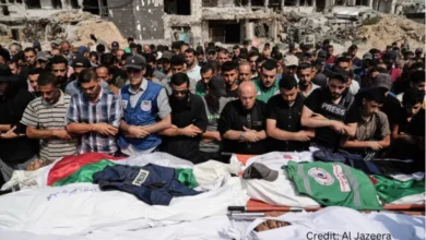 Palestinian cameraman filming in front of rubble wearing a press vest after an airstrike in Gaza City