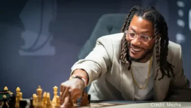 Derrick Rose focuses on a chess move during Chesstival with Magnus Carlsen watching