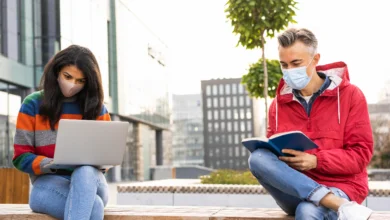 after high school in B.C. two diverse teens study together outdoors on a modern campus, using a laptop and a book to explore future options.