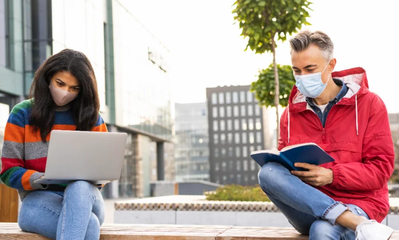 after high school in B.C. two diverse teens study together outdoors on a modern campus, using a laptop and a book to explore future options.