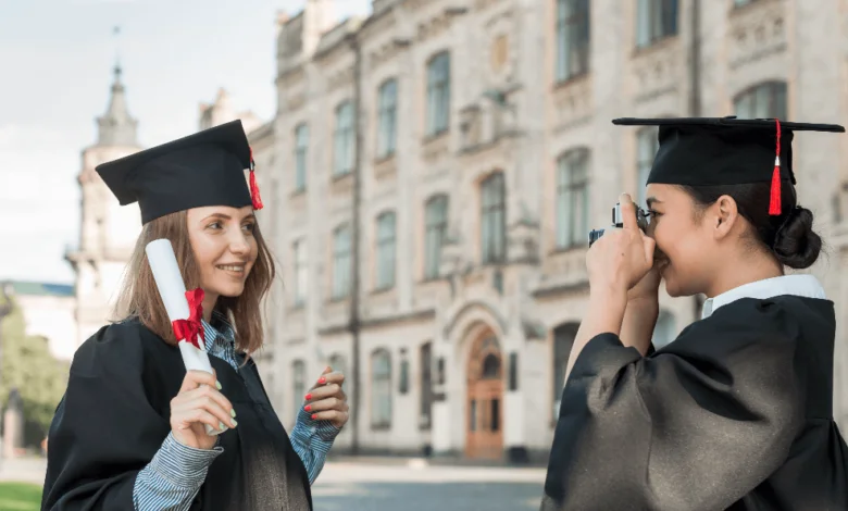 best colleges in British Columbia two graduates in caps and gowns celebrating with a diploma outside a historic campus building.