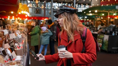 Woman browsing vendor stalls during the Downtown Abbotsford Holiday Sip & Shop, holding a warm drink while exploring handmade goods at a festive outdoor market.