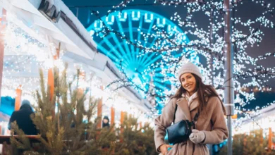 Visitor enjoying illuminated displays at the Surrey Winter Light Program with festive trees and bright lights in the background.