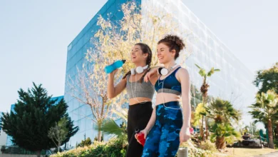 Two women enjoying a break after an outdoor workout during Vancouver pop-up fitness events in a sunny city park.