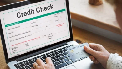 Person checking credit score in Canada on a laptop while holding a credit card and reviewing financial details