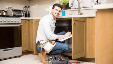 Drain cleaning cost in Canada with plumber inspecting kitchen sink pipes and fixing clogged drain