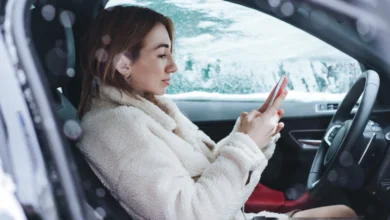 Driver sitting in car using phone during winter showing how driving in Canada is changing in daily life